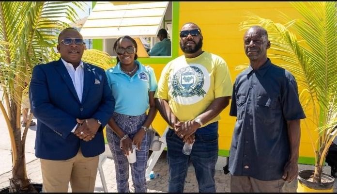 Four people, one in a United Against Crime shirt, stand in front of a yellow kiosk at the expo