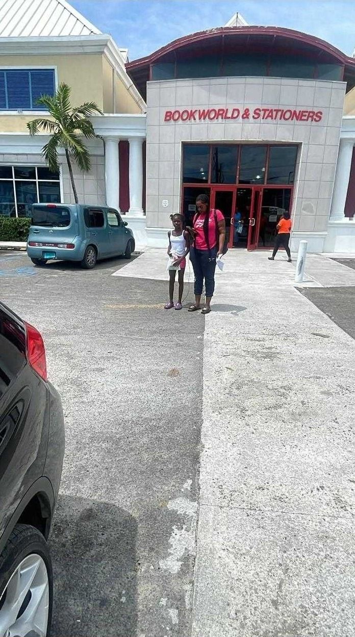 A girl and a woman stand outside the Bookworld and Stationers store during back-to-school shopping