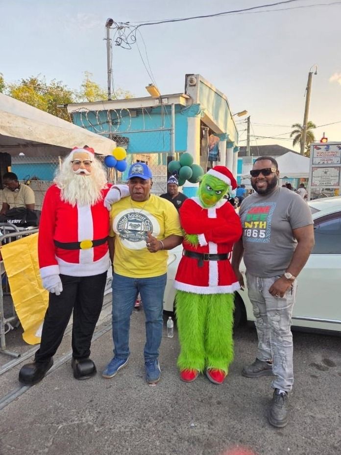 Santa, a costumed Grinch and two men, one in a United Against Crime shirt, pose in the street