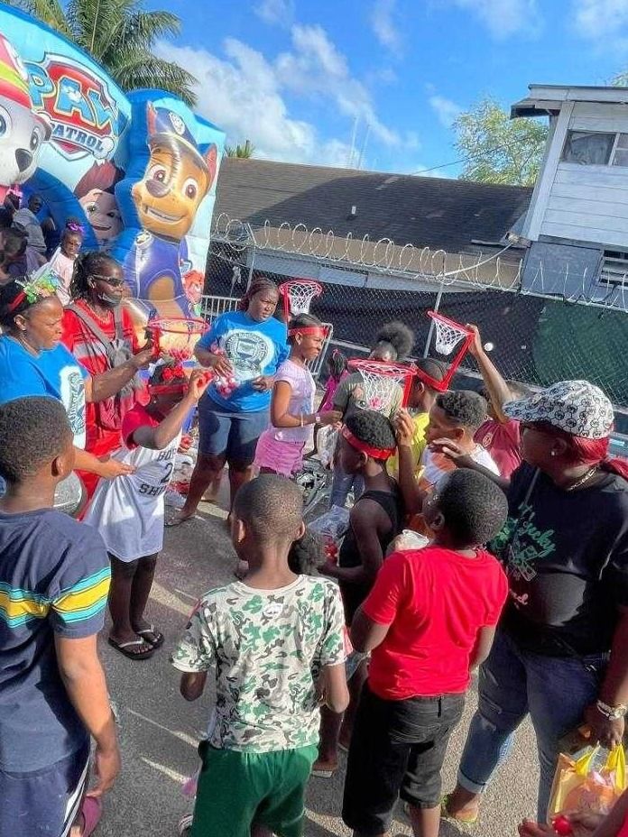 Children and volunteers play a mini basketball hoop game beside a Paw Patrol bounce house