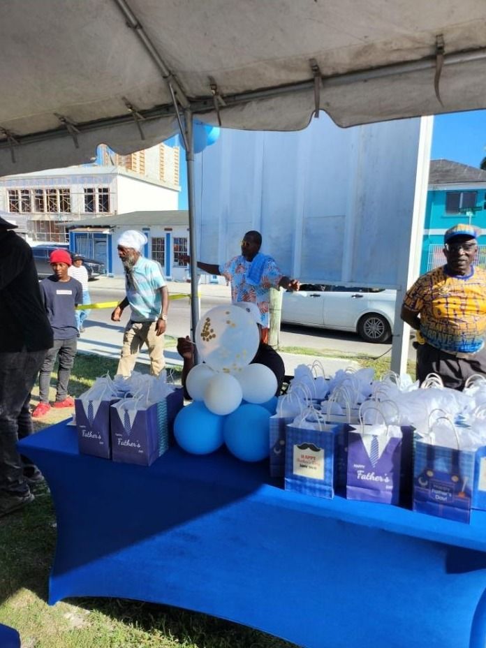 Father's Day gift bags and balloons are arranged on a blue table under a tent