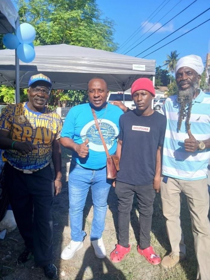 Four men pose outdoors, two giving thumbs up, one in a blue United Against Crime shirt