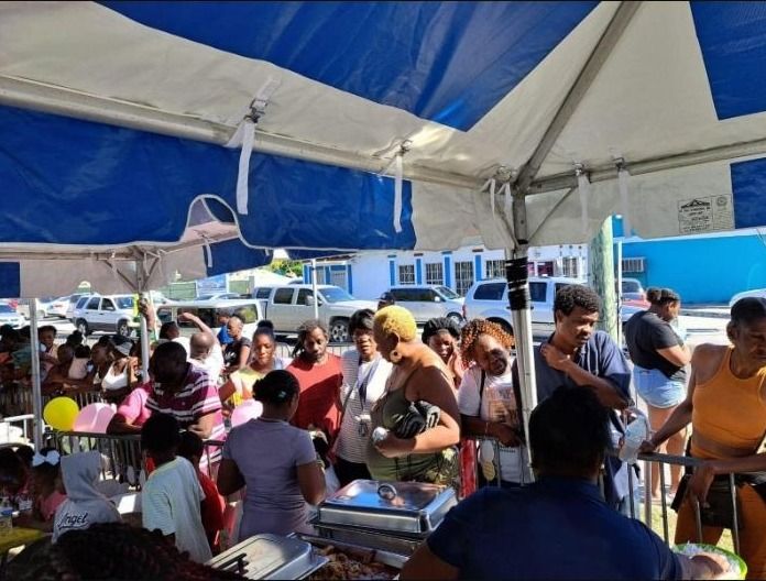 Guests queue at chafing dishes of hot food under a blue and white tent