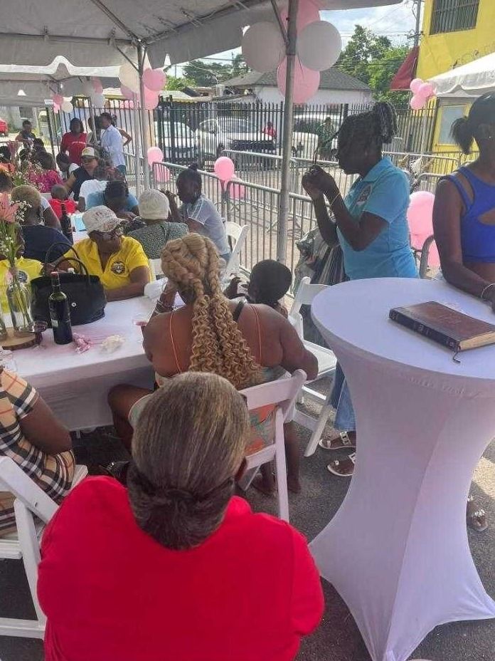Guests seated at tables under a tent with pink and white balloons, with a Bible on a standing table